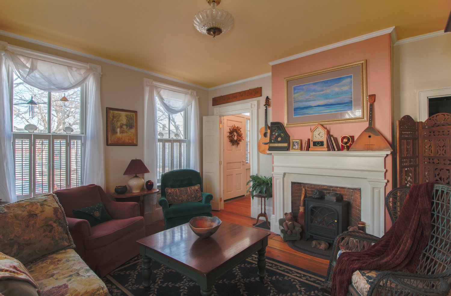 The narrow wall above the fireplace, painted a muted salmon, provides a striking backdrop for the seascape painting while connecting with the floors below